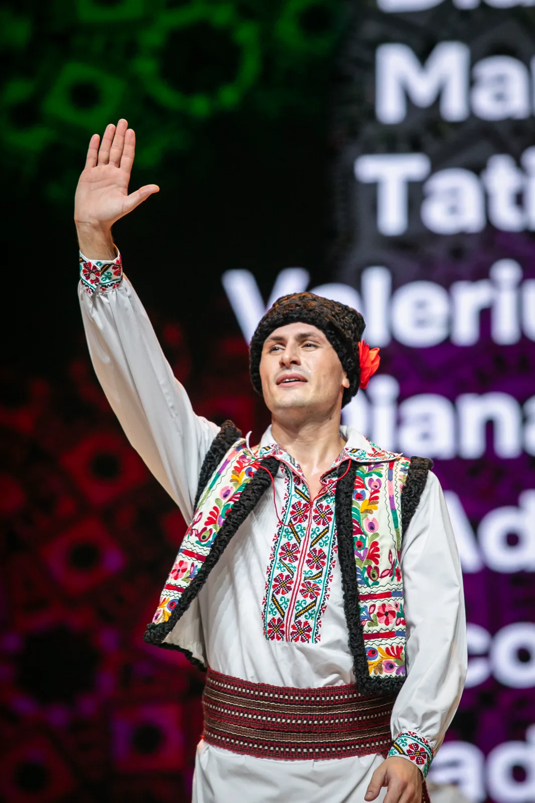 Artist JOC în costum tradițional, cu brațul ridicat