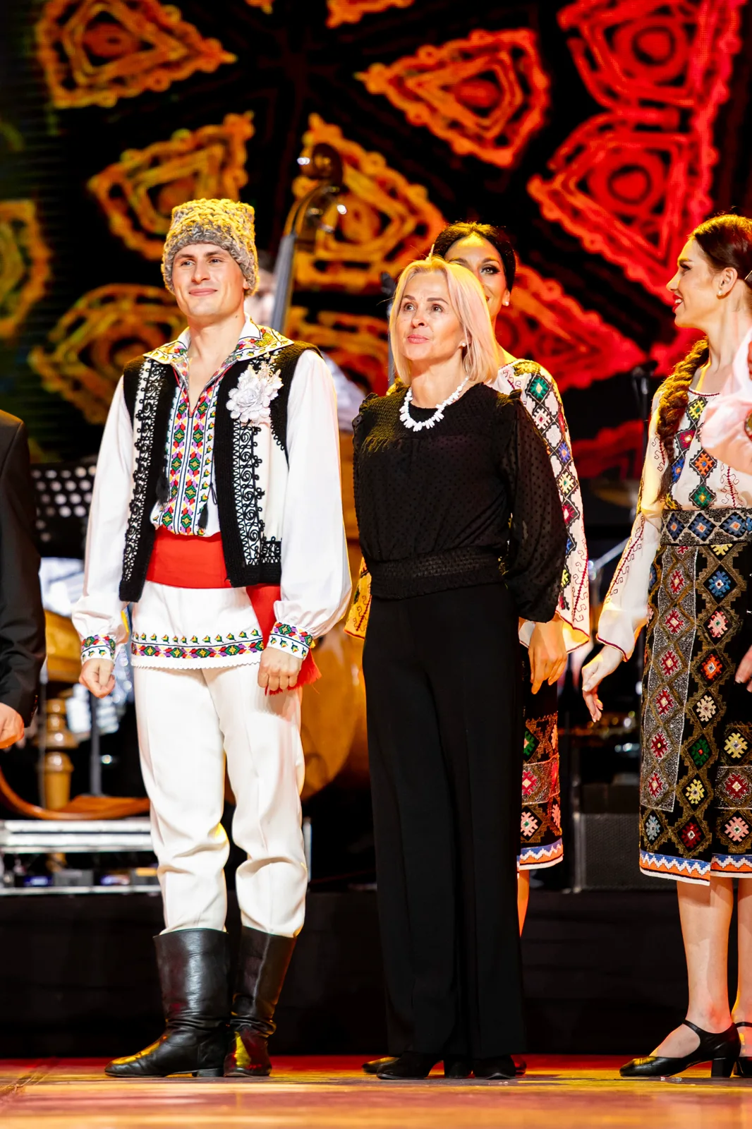 Artist în costum popular alături de o invitată pe scenă